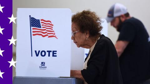 A woman at a voting booth, a man is also voting in the background