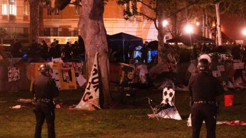 Two police officers stand in front of a pro-Palestine encampment at USC