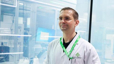 Alex Zhavoronkov wearing a white coat stands in his company's lab