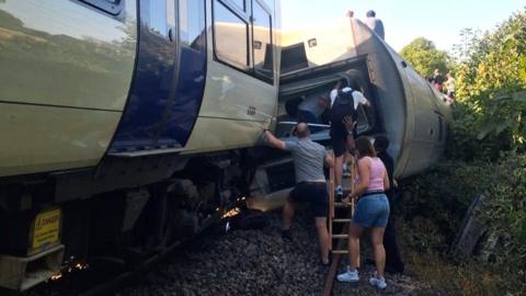 People getting out of an overturned train.