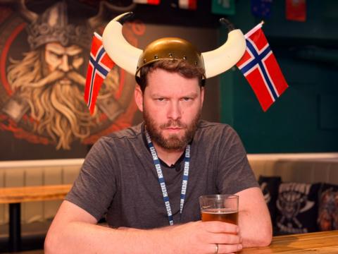 Bard Aune, BBC journalist, sat in a bar surrounded by viking paraphernalia, is pulling an angry face with viking horns on his head