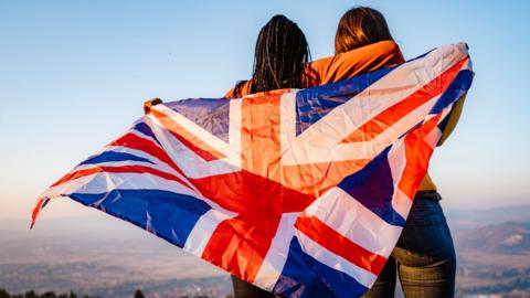 Two young women holding a Union Jack flag. 