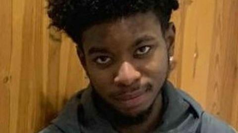 Robert Robinson smiles with his arms folded. He wears a grey zip-up hoodie.