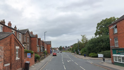 Newtown Road in Carlisle. Is it a wide street with red brick terraced houses on the left-hand side of the road, facing a park. 