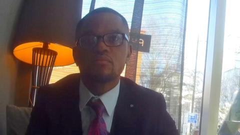 Undercover footage of a man in a suit, wearing glasses, in a hotel lobby.