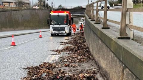 Leaves being removed from the roadside in Bradford by refuse workers.