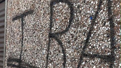 IRA in black spray paint on a pebbledashed wall