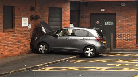 view showing a car crashed into the wall of a GP surgery, next to a boots pharmacy