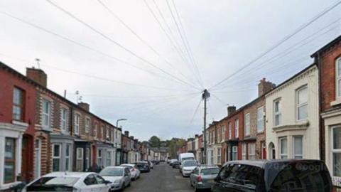 Inner city street of terraced houses with parked cars.