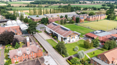 An aerial view of the buildings at the university campus. They are separated by paths and green fields.