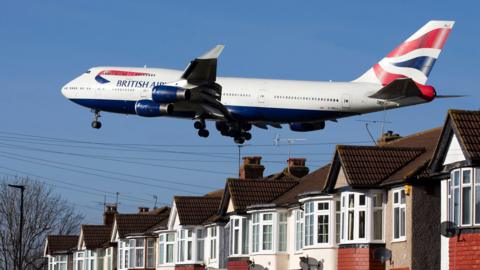 A British Airways 747 plane flies over roof tops as it comes into land at Heathrow Airport in London