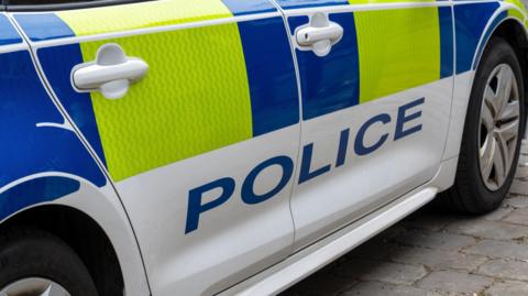 Close up of a United Kingdom police patrol response car with Battenberg markings.
