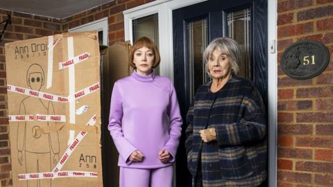 Diane Morgan as an uncanny android called Linda, Sue Johnston as Sue, and a large empty cardboard box in Ann Droid