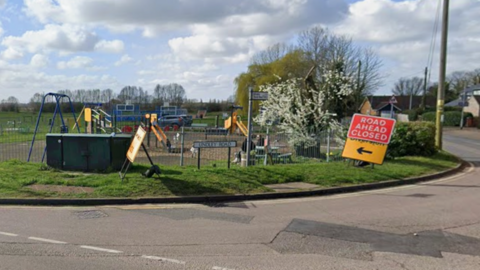 Undley Road sign at a junction. There is a Road Ahead Closed sign next to it and a children's playground in the background.
