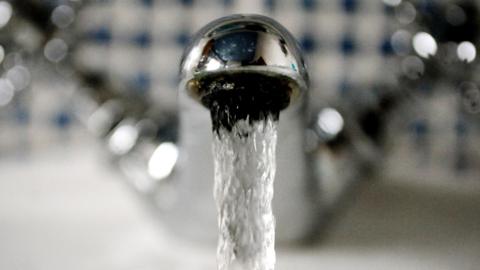 A stream of water falls out of a sliver tap. 