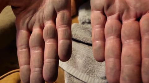 A pair of hands outstretched covered in black dust above a dirty white towel