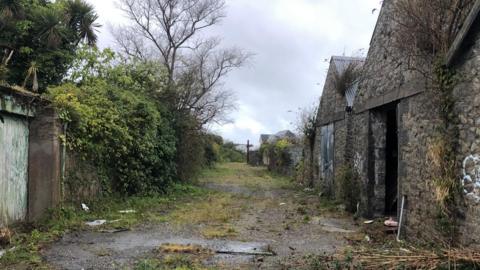 A derelict site with brick building son the right. 