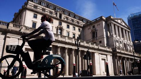 A man on a bicycle cycles past the Bank of England building