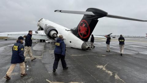 National Transportation Safety Board (NTSB) investigators inspect the wreckage of an Air Canada Express jet that collided with a fire truck at LaGuardia Airport in Queens, New York
