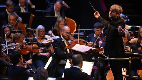 A conductor leads an orchestra during a performance at the Royal Albert Hall.