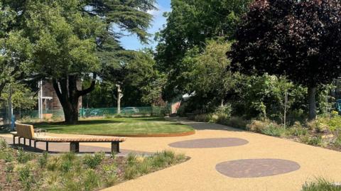 The Peace Garden has wooden benches and a pathway around a green lawn.