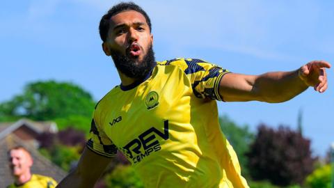 Deon Moore sticks his arms out wide as he celebrates scoring for Torquay United