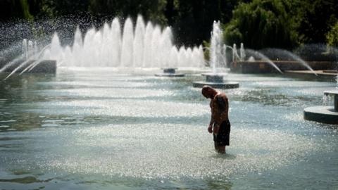 Man standing in water fountain in Battersea Park, London.