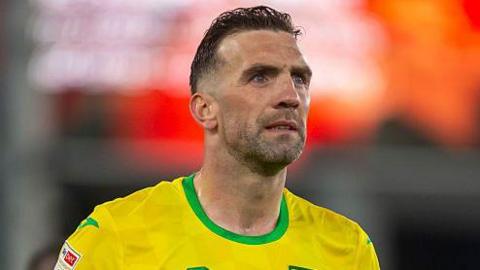 A head and shoulders image of Shane Duffy pictured during a football match. He is wearing a yellow football top with a green neckline  