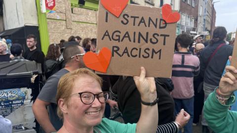 Woman holding a sign which says 'I stand against racism'