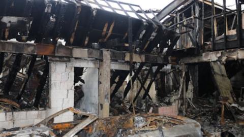 The burnt out shell of the workshop building showing charred remains and no roof