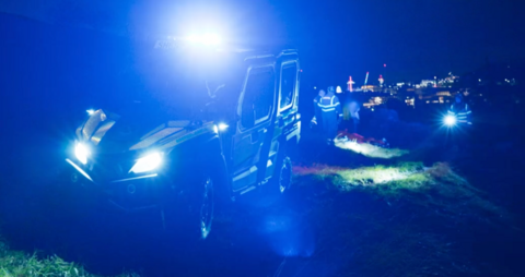 A wolverine vehicle at night with its headlights flashing