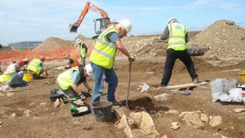 Men in high-vis vests digging up ground.