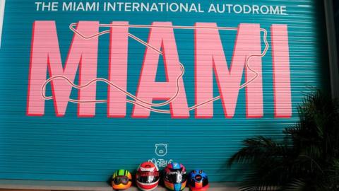 An image of four race helmets underneath a Miami sign 