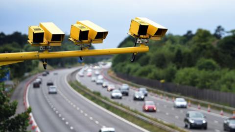 Yellow ANPR cameras on a mast above a motorway