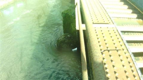 A high water level next to a railway track. There is a white marker on the bridge and the water is above it.