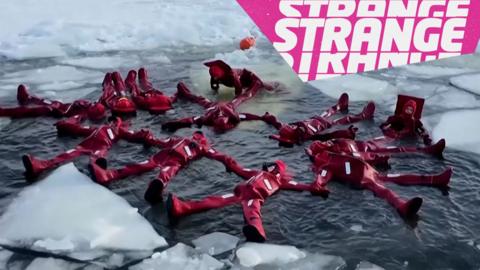 People in red thermal suits floating in the icy water