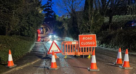 A closed road with traffic cones and signs