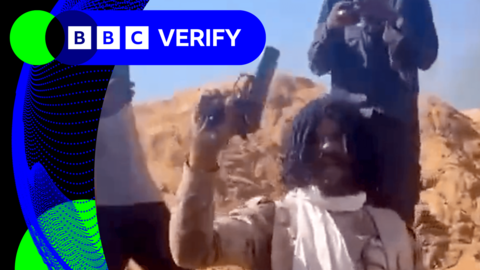 A man in camouflage holding a pistol in the air