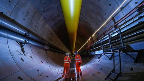 Two workmen wearing bright orange stand inside the HS2 Bromford Tunnel 