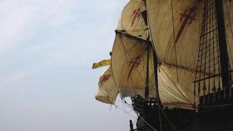 The reproduction sailing ship Nao Victoria in full sail at sea. With its cream sails billowing.