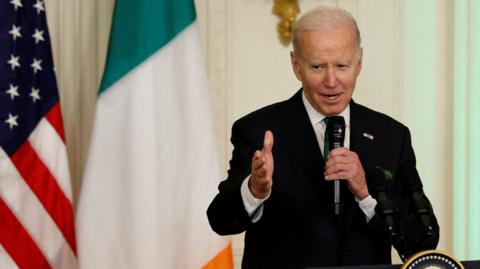 President Biden standing at a podium, with US and Irish flags behind him