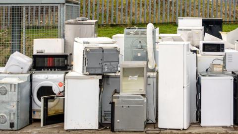 A pile of old fridges, freezers, and other household appliances