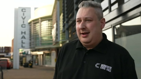 A man in a black Bedworth Civic Hall polo shirt stood outside the venue