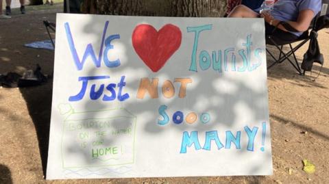A handmade poster saying "We love tourists, just not so many."