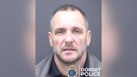 A mugshot of a man with Dorset Police's logo in the bottom right corner