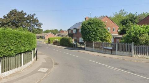 A brick house with trees in the garden and a fence around it at the end of Mason Avenue in Swallownest