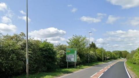 The A428 near Eltisley showing a single carriaway road and a sign on the left signposting to Waresley, Brandons and Eltisley