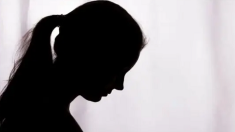 A generic image of a woman in silhouette looking down. The woman has her hair up in a ponytail. 