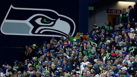 The Seahawks logo, pictured next to a crowd of fans