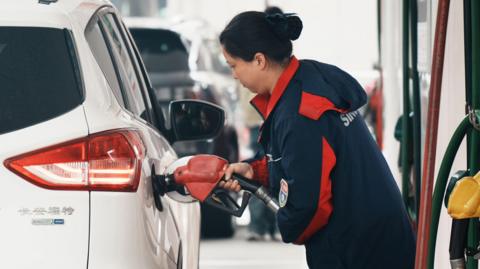 A staff member refuels vehicles at a Sinopec gas station in Hangzhou City, Zhejiang Province, China on 23 March, 2026